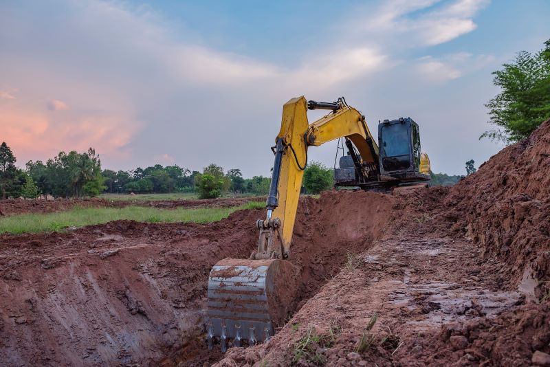 Empresa de terraplenagem: retroescavadeira realizando a terraplenagem em terreno.