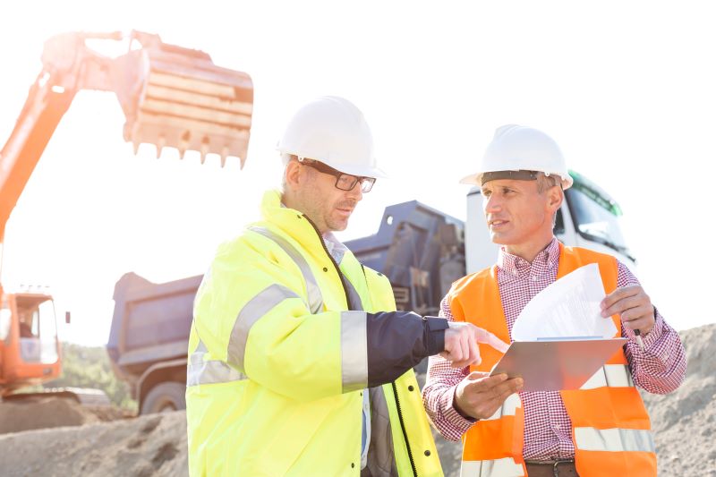 alugar caminhão munck​: engenheiros em obra conversando e analisando documentos
